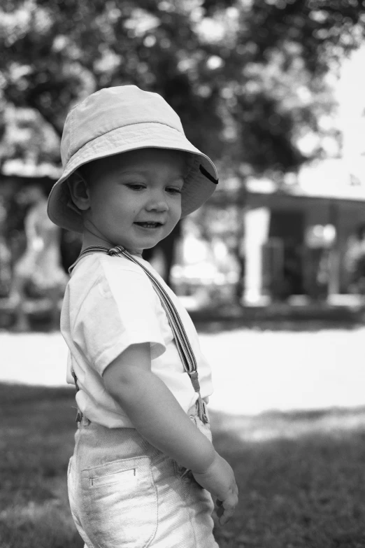 small child standing in grassy area next to trees