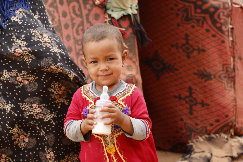 a child that is standing with a bottle