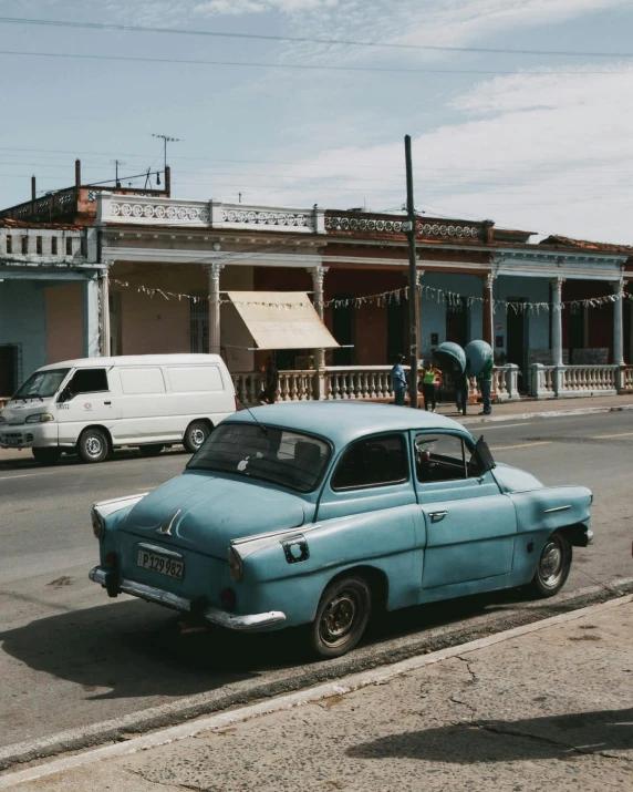 a small car driving down the side of a road