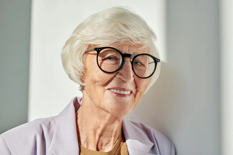 an older woman wearing glasses smiles at the camera