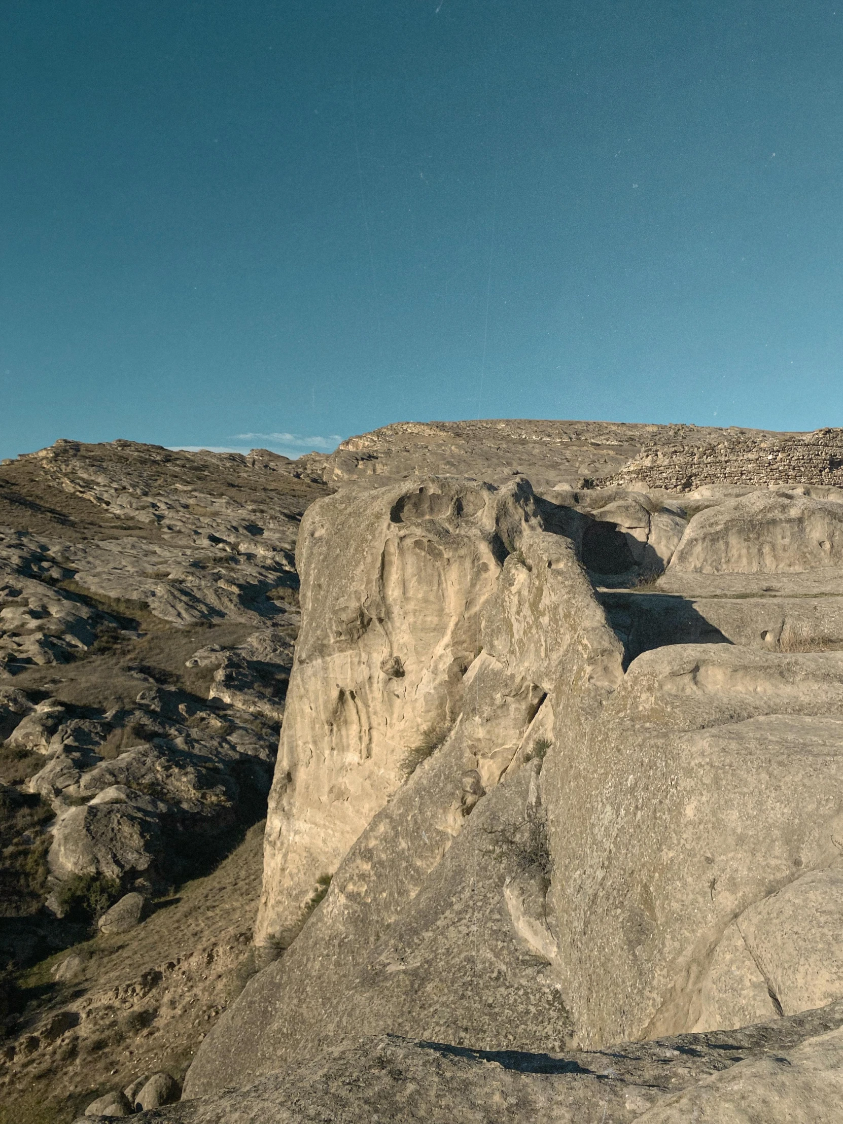 the man is standing on a cliff looking over a vast mountain area