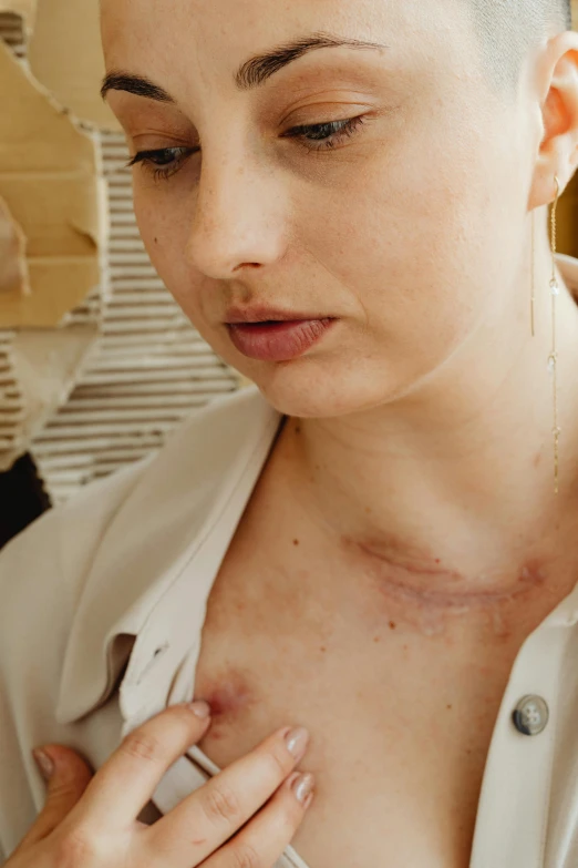 woman looking down and holding cellphone with scar on her neck