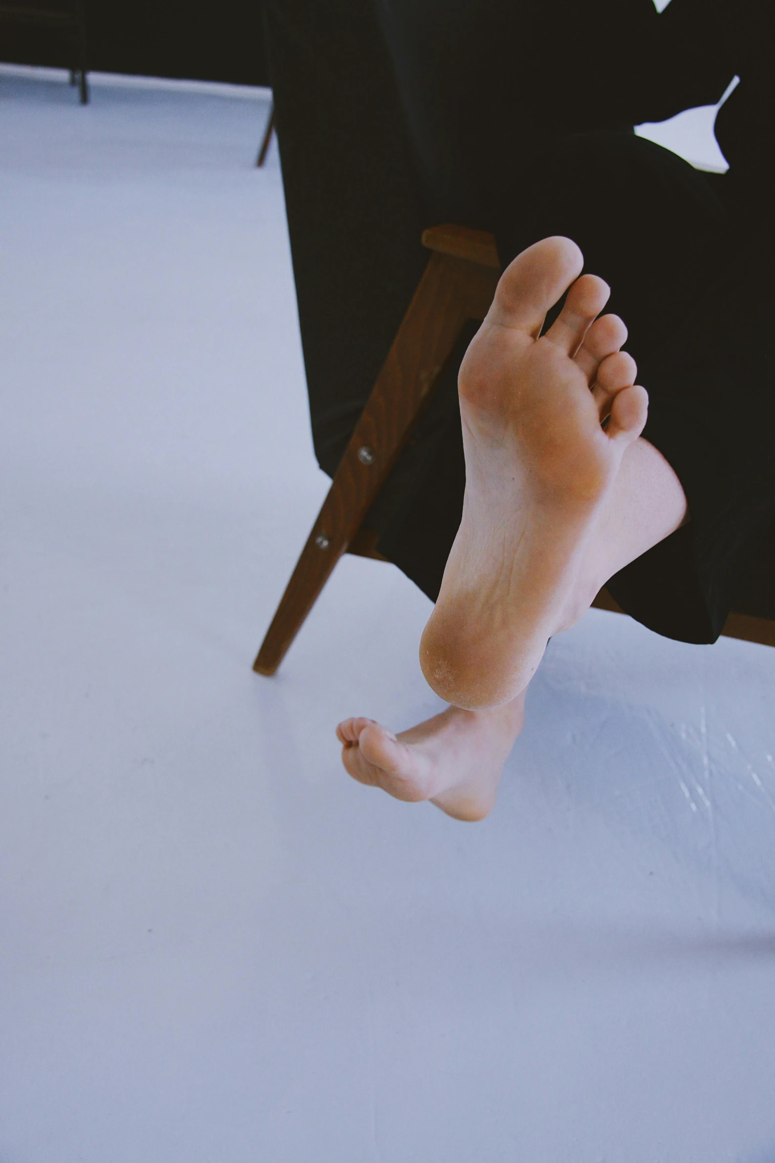 bare feet and legs of someone sitting in a chair