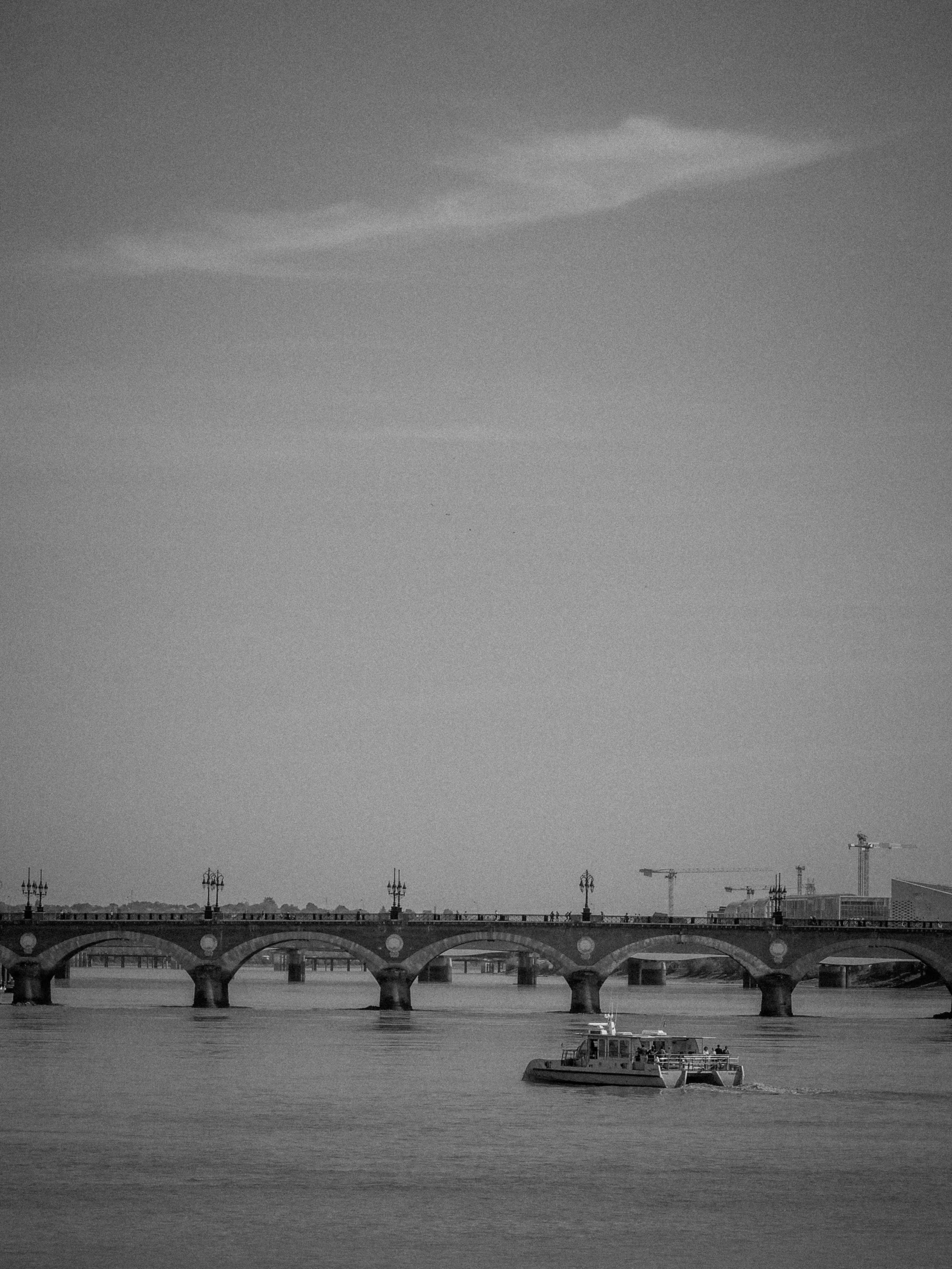 a boat traveling along the water by a bridge