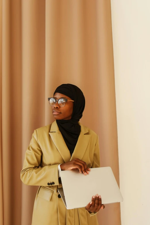 a woman in glasses holding a folder and wearing a yellow suit