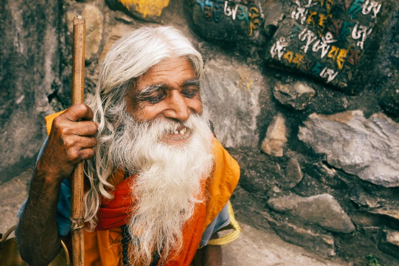 the man with white hair and long beard is holding a stick