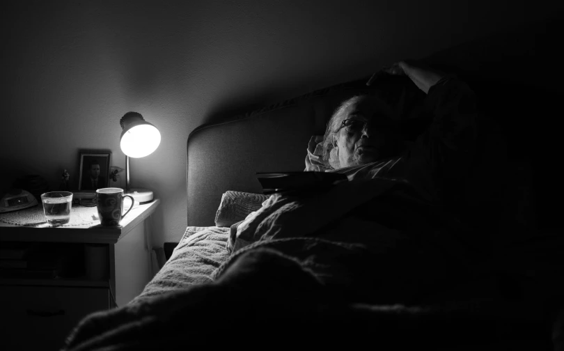 a person laying in a bed under a lamp