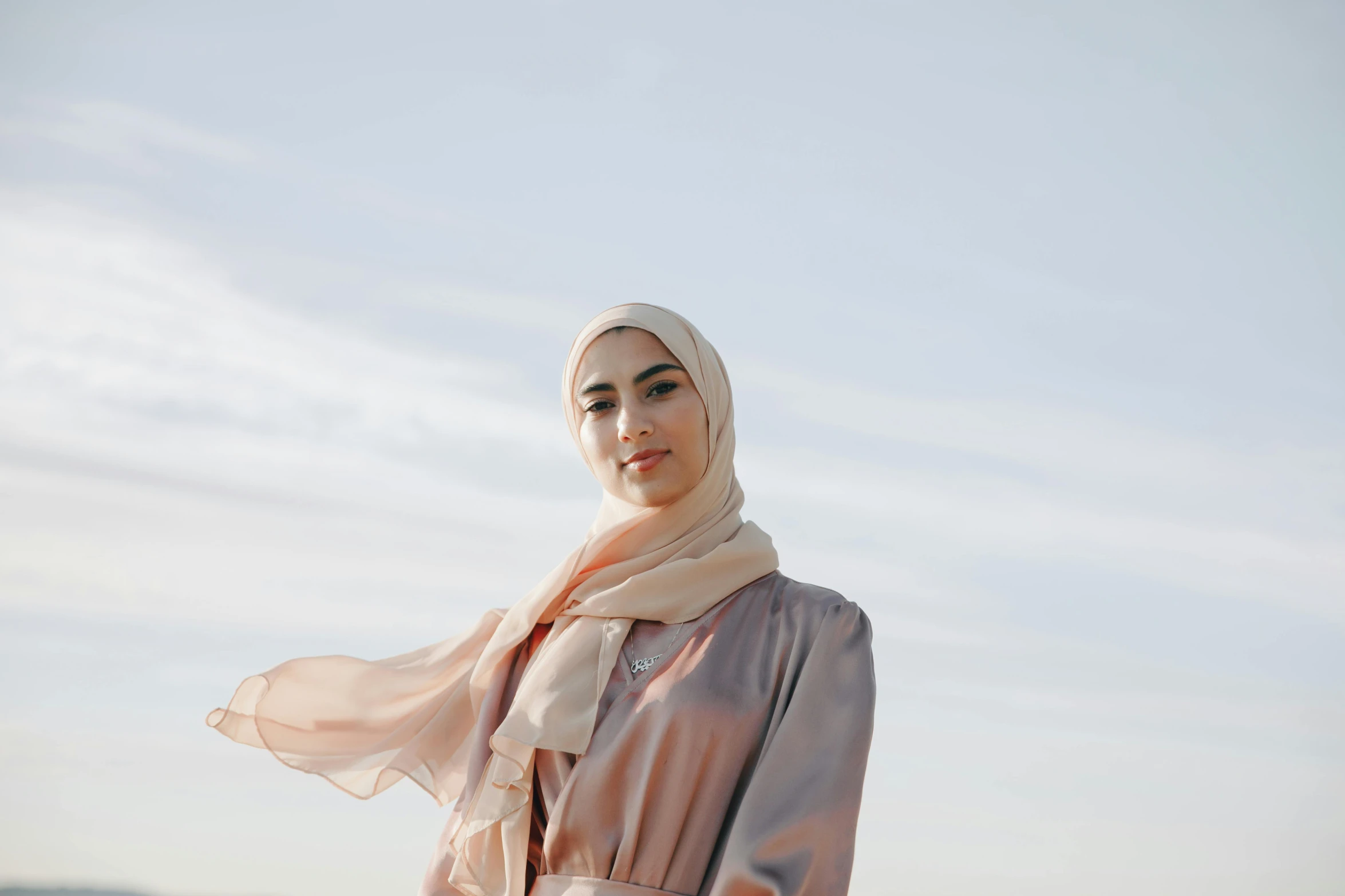 a woman wearing a hijab standing by the ocean