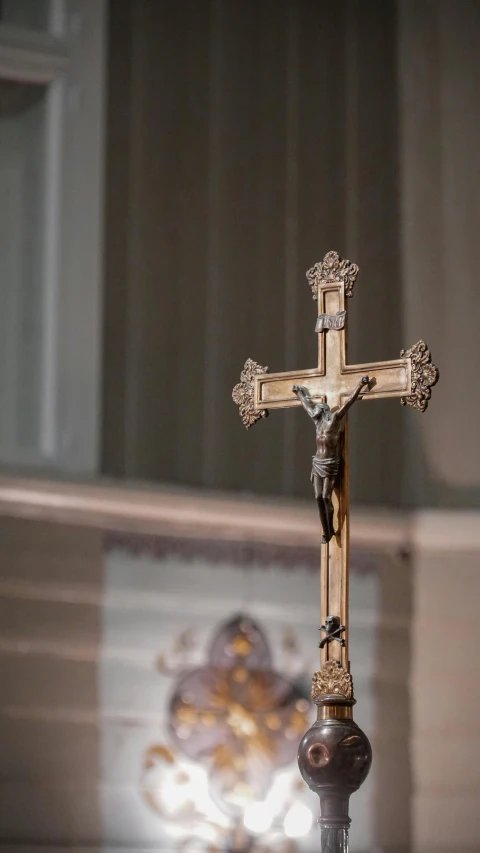 a cross and lights in a room with window curtains