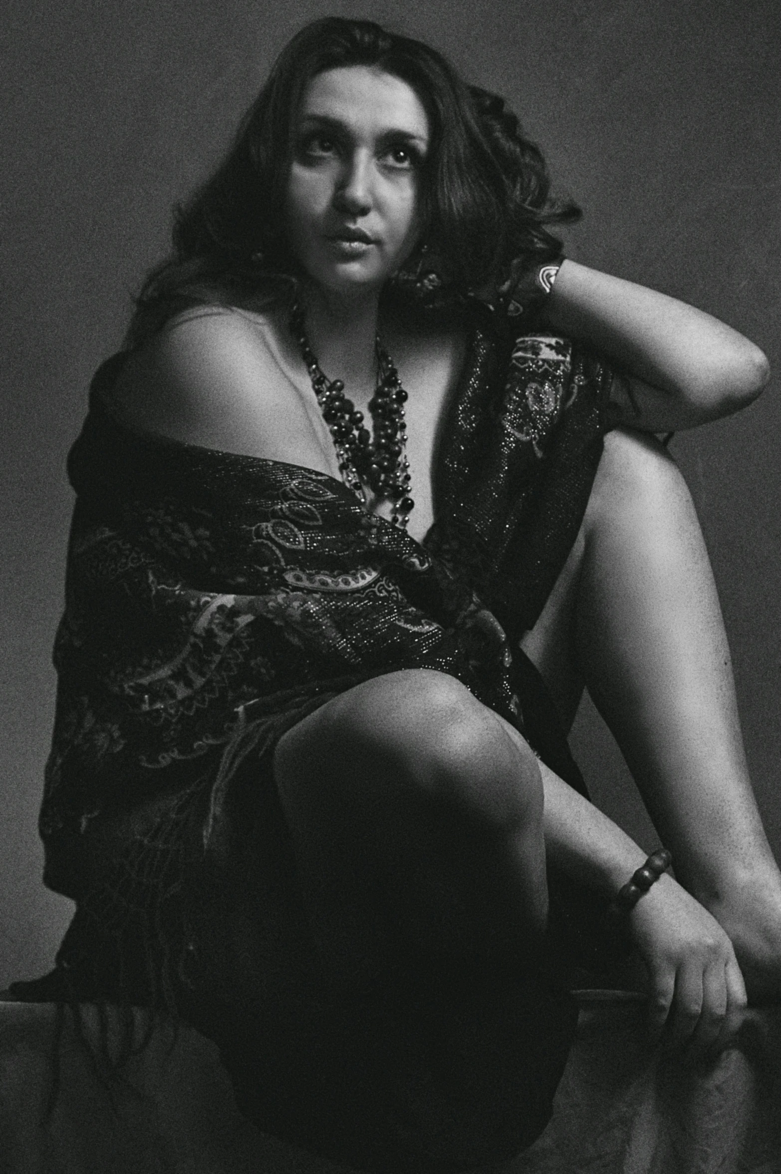 a woman with her hands on her shoulder, sitting against a table