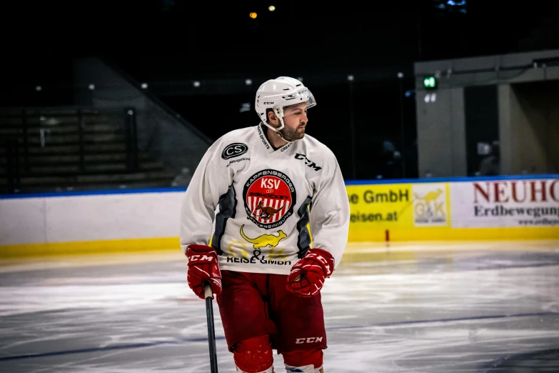 a man standing on a ice rink with hockey sticks