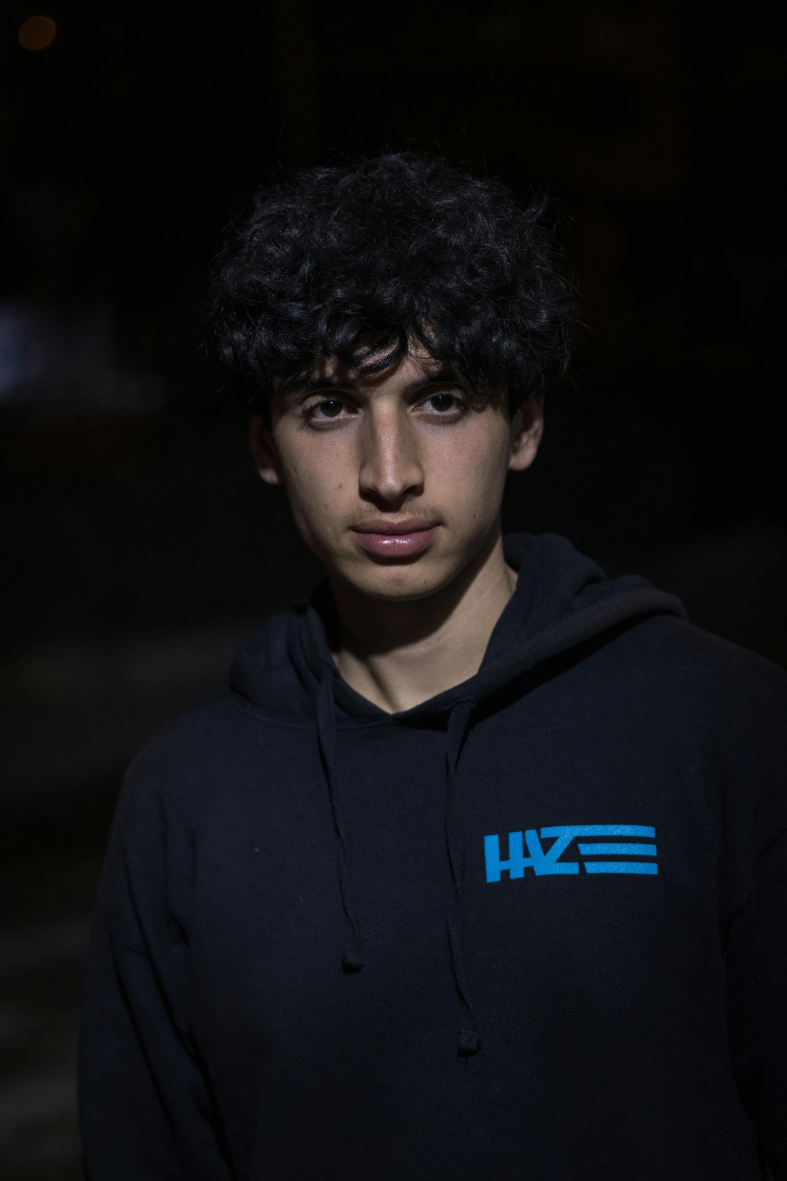 a young man with dark eyes is wearing a hoodie