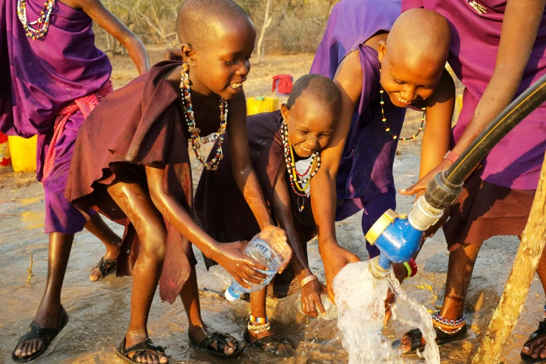 children fill a water spout with a bucket