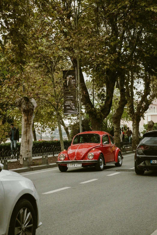 a small car driving down the street with other cars nearby