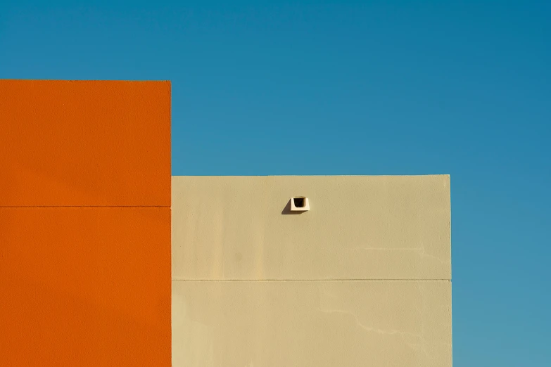 a orange building is by a very blue sky