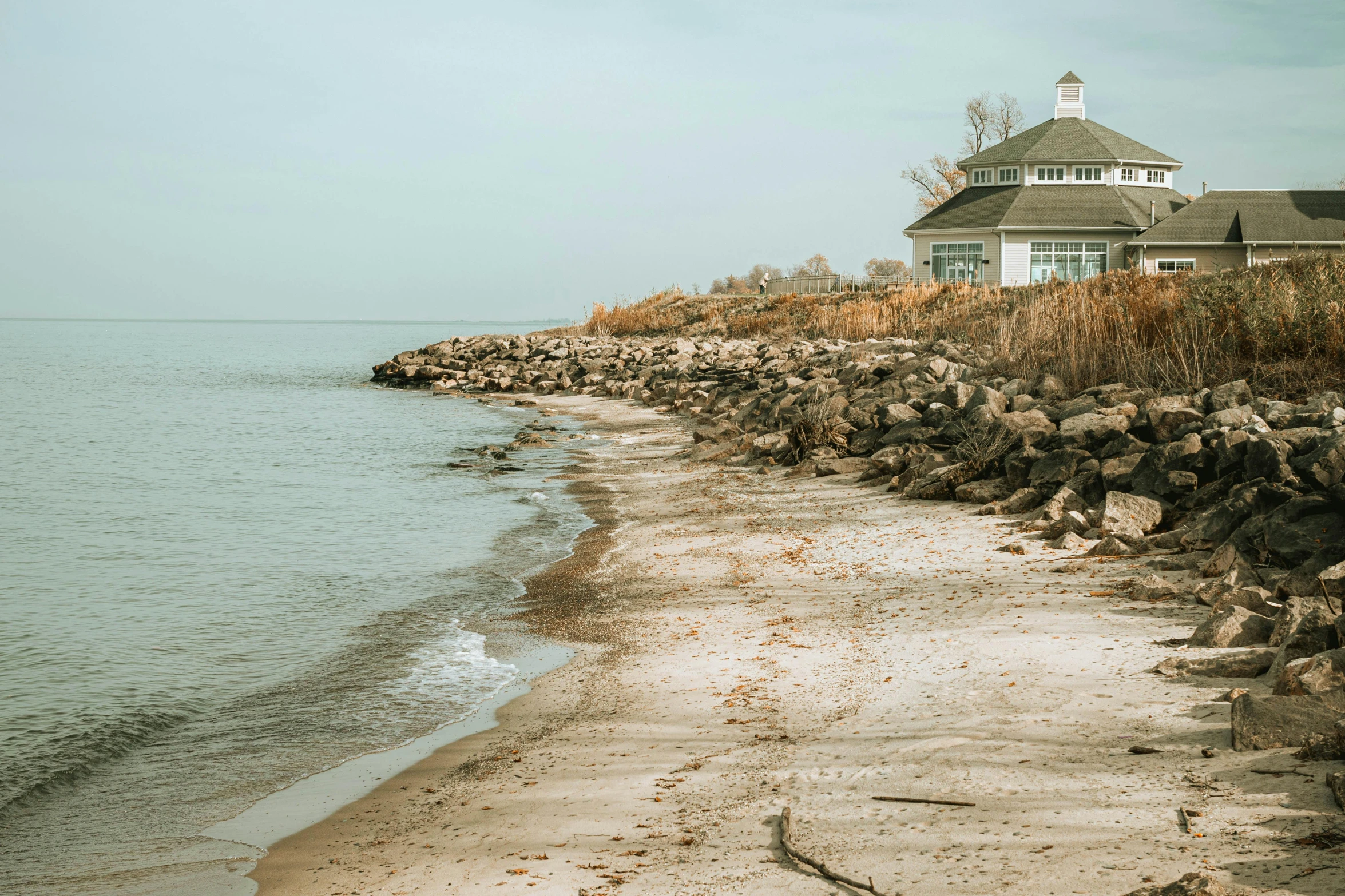 a house sitting on top of a beach next to the ocean