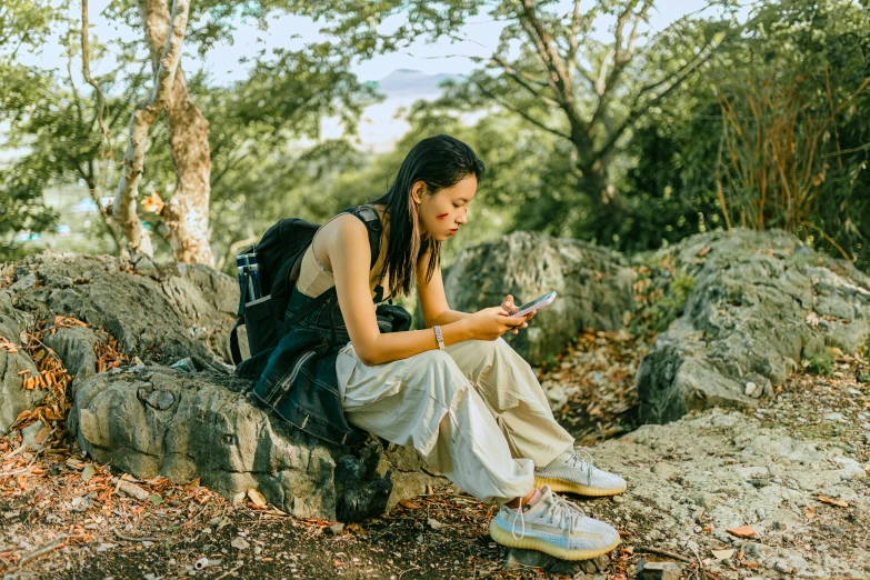 a woman with ids sitting on a rock with a cell phone