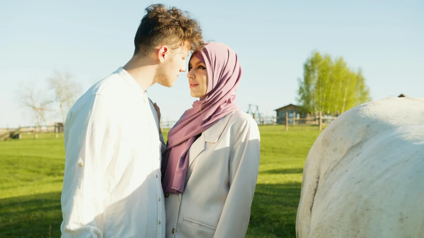 a man and woman stand close to each other near a cow