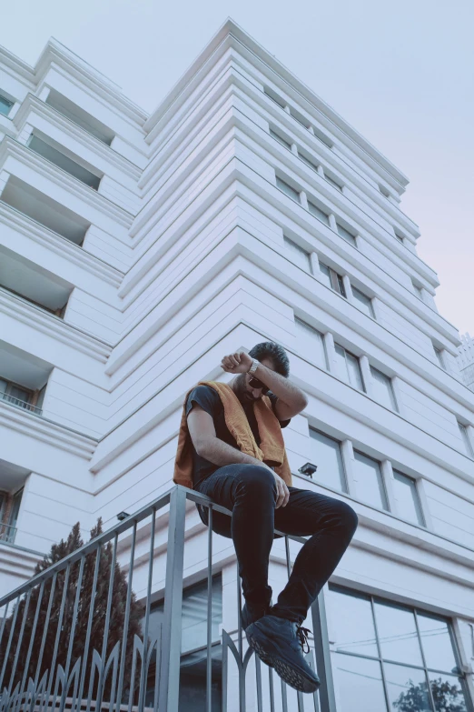 there is a man sitting on the railing on the cell phone