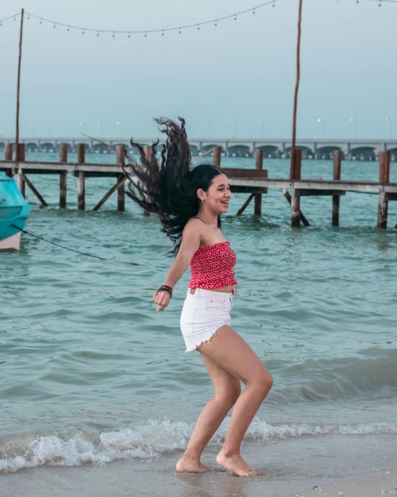 a woman with a red top running along the beach