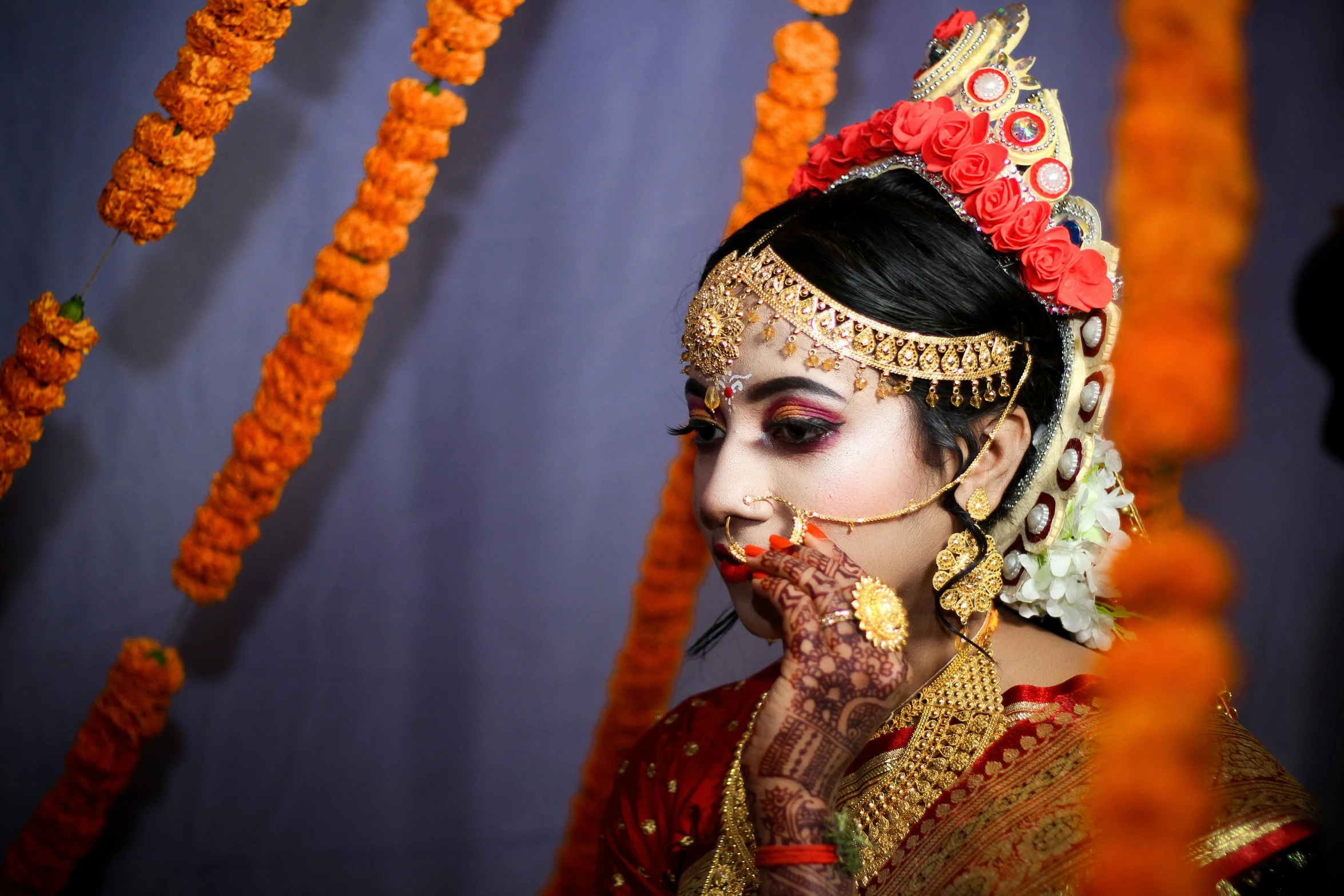 a woman in a traditional outfit stands before flowers