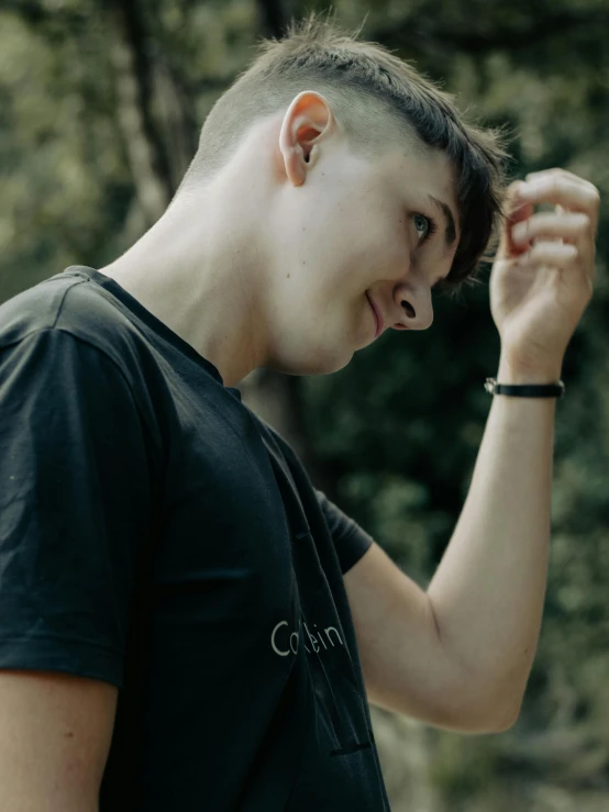 a young man in a black shirt is holding his ear up