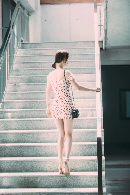 a woman in a pink dress standing on some stairs