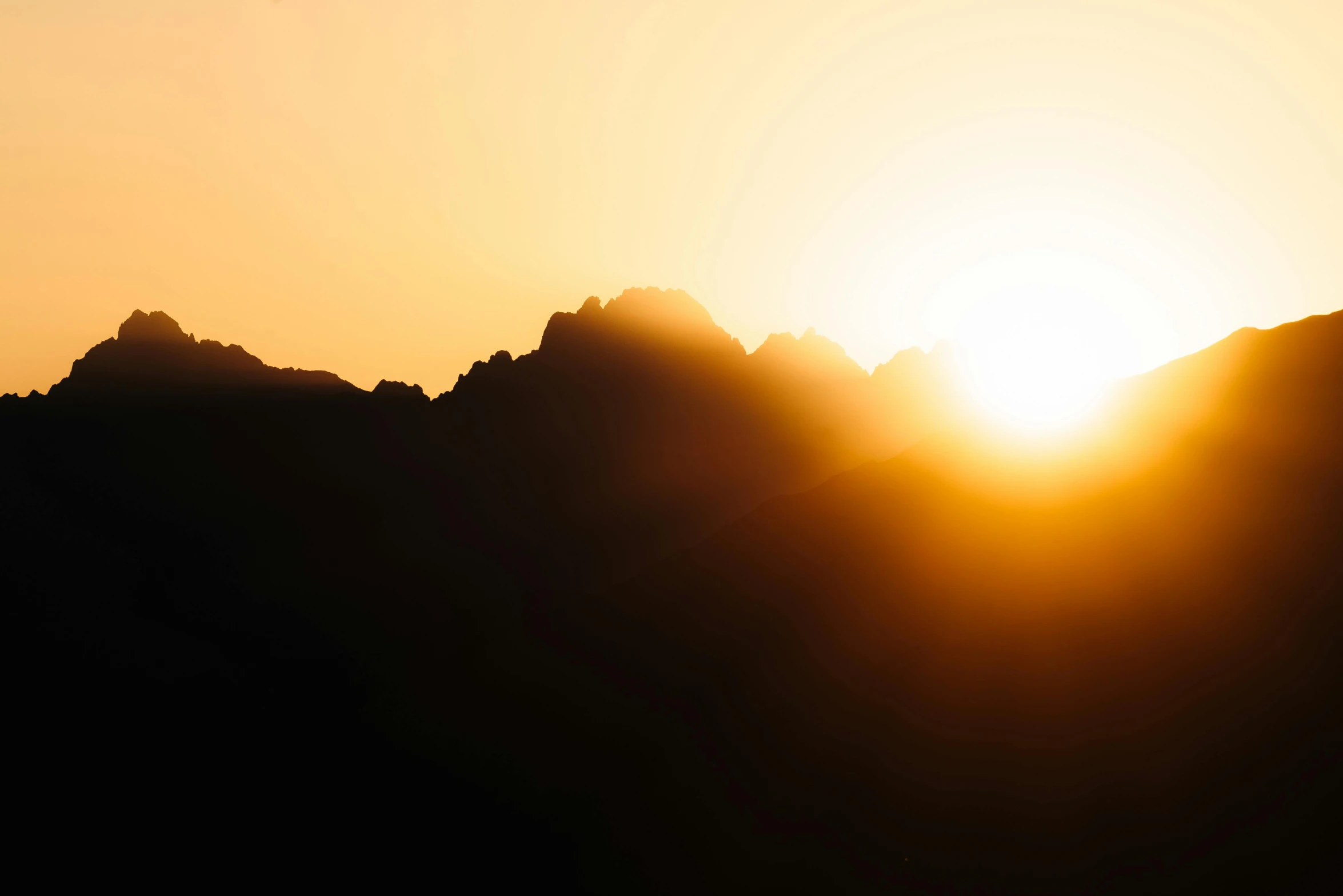 a yellow and orange sunset over a mountain range