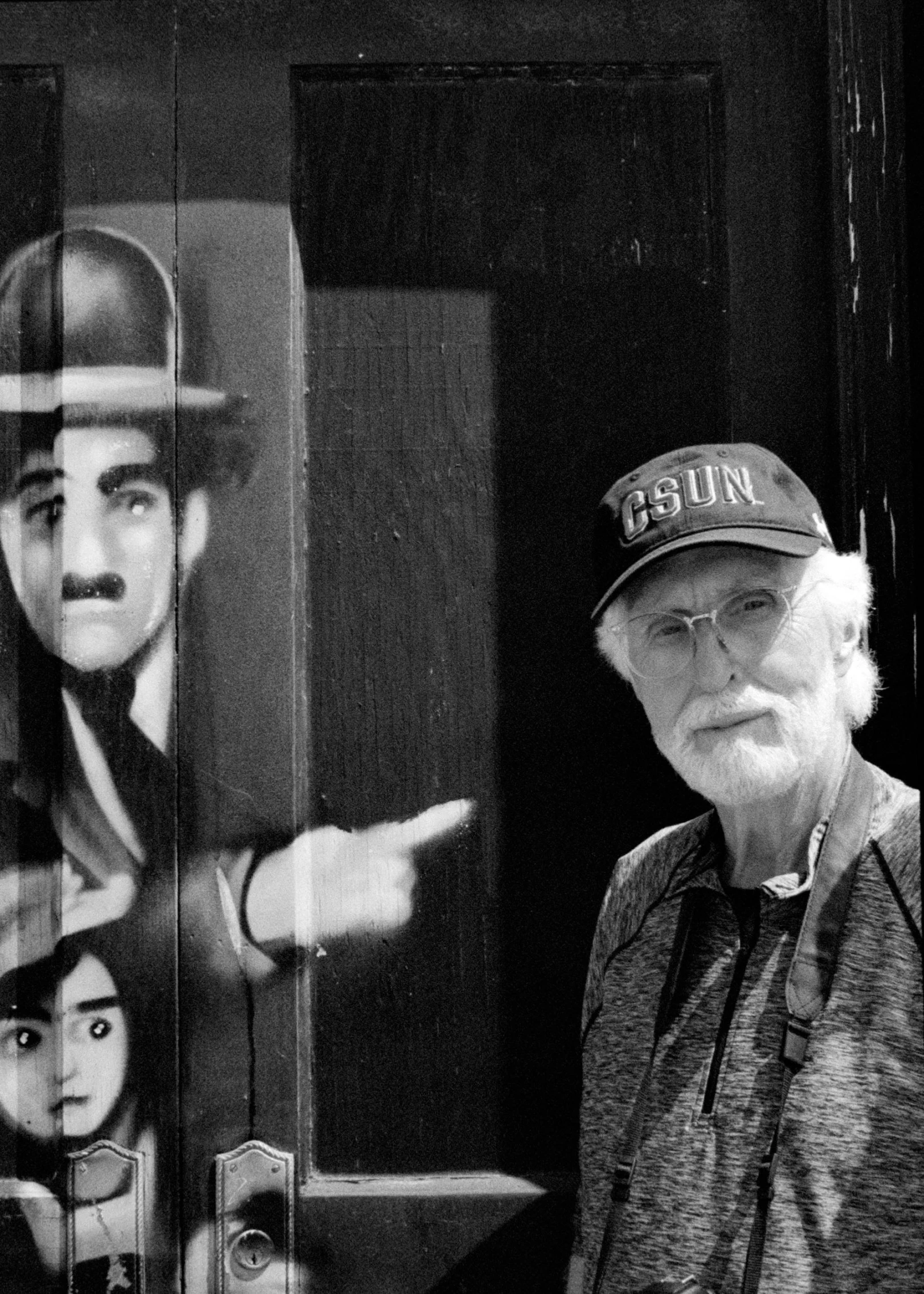 the man is holding his hands out while standing next to a mural of the movie hero