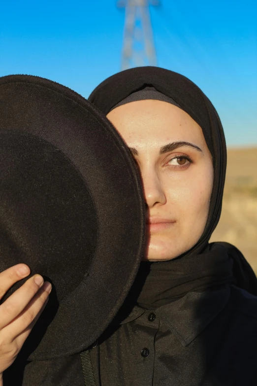 a woman wearing a black hat next to a windmill