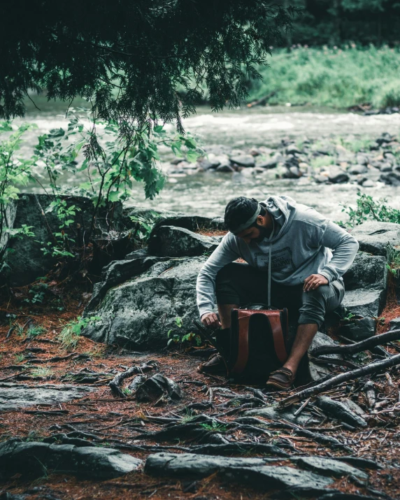 a man sitting on rocks next to a river