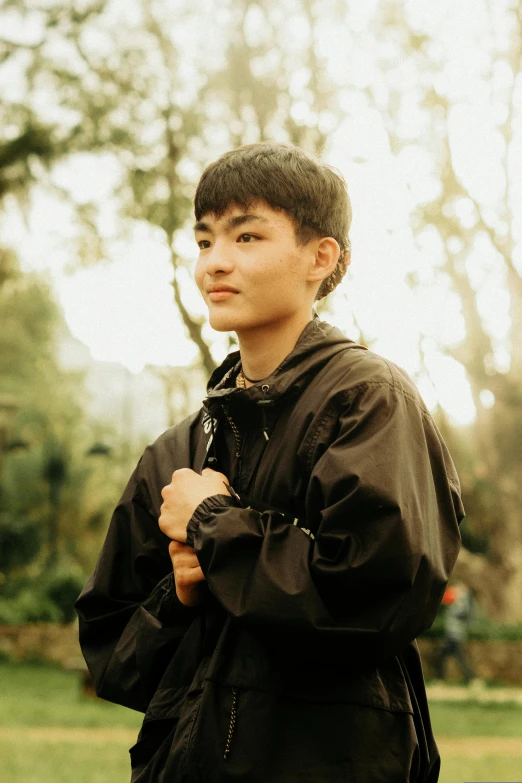 a young asian boy stands outside in the sun