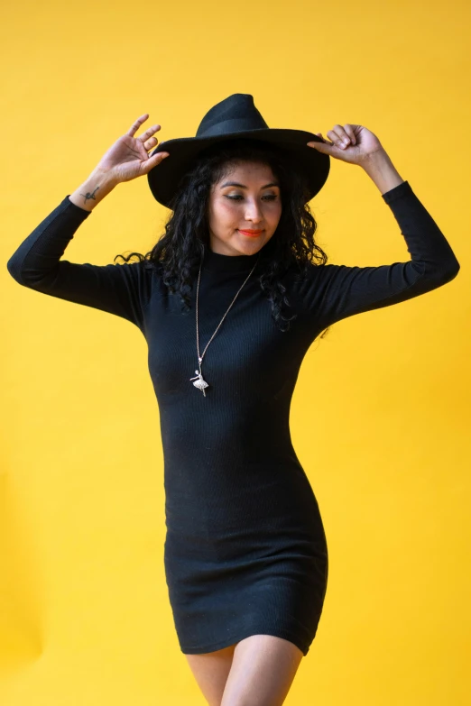 a young woman poses wearing a black hat and dress