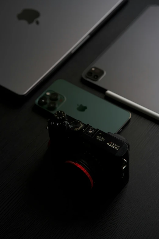 an apple laptop sitting next to a camera with a few other devices