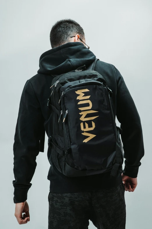 man standing wearing a backpack with the words kanon on it