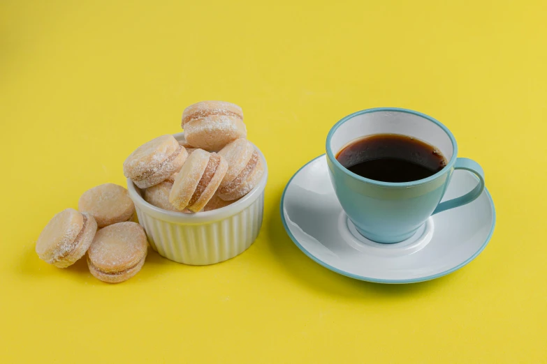 a cup of coffee and a plate of donuts on a yellow background