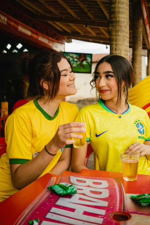 two women sitting at a table drinking orange juice