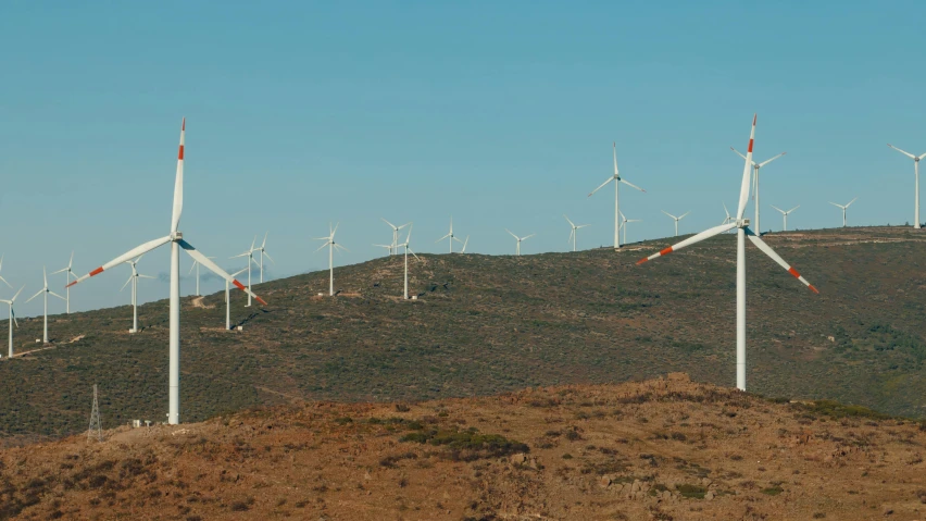 many windmills stand on top of a hill