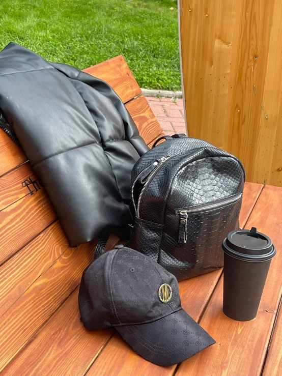 hat, coffee cup and black handbag on a bench