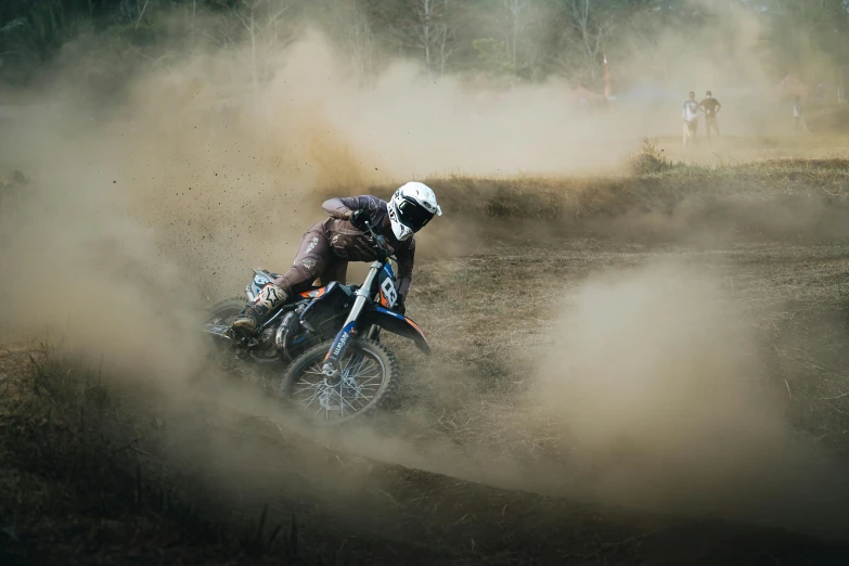 dirt bike rider turning around a trail of dust