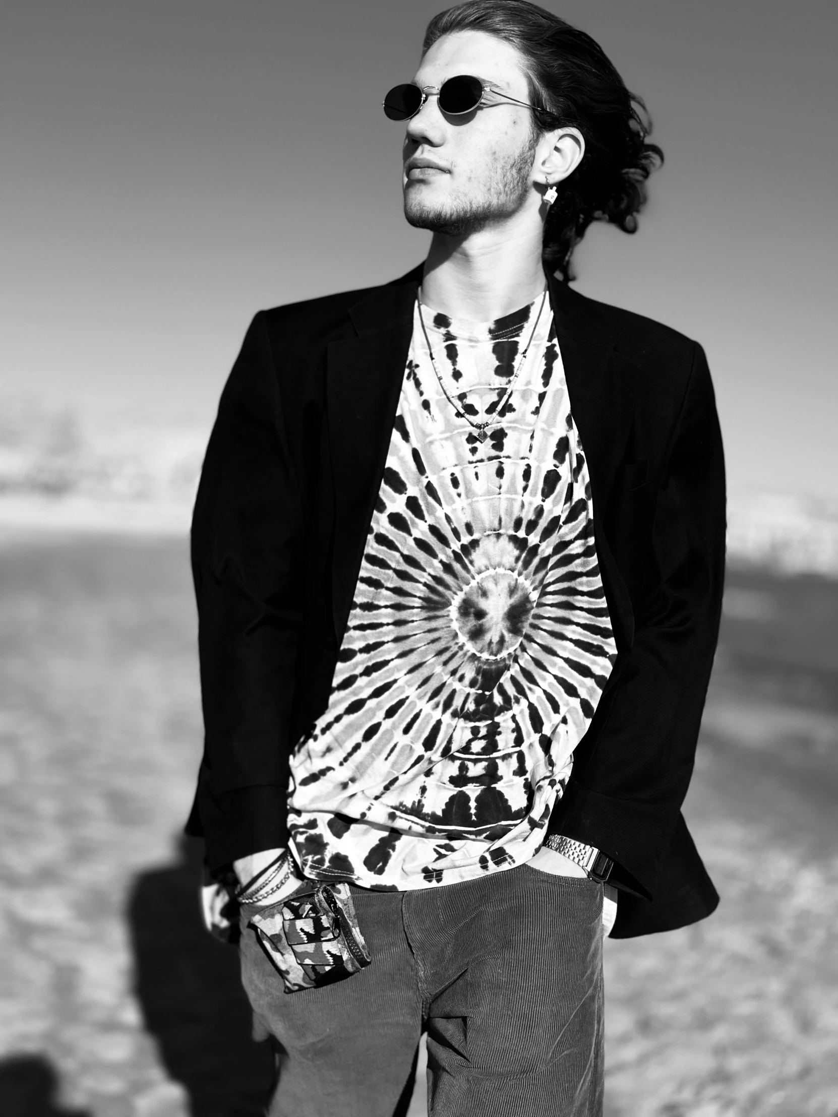 man standing on beach with sunglasses and shirt over his head