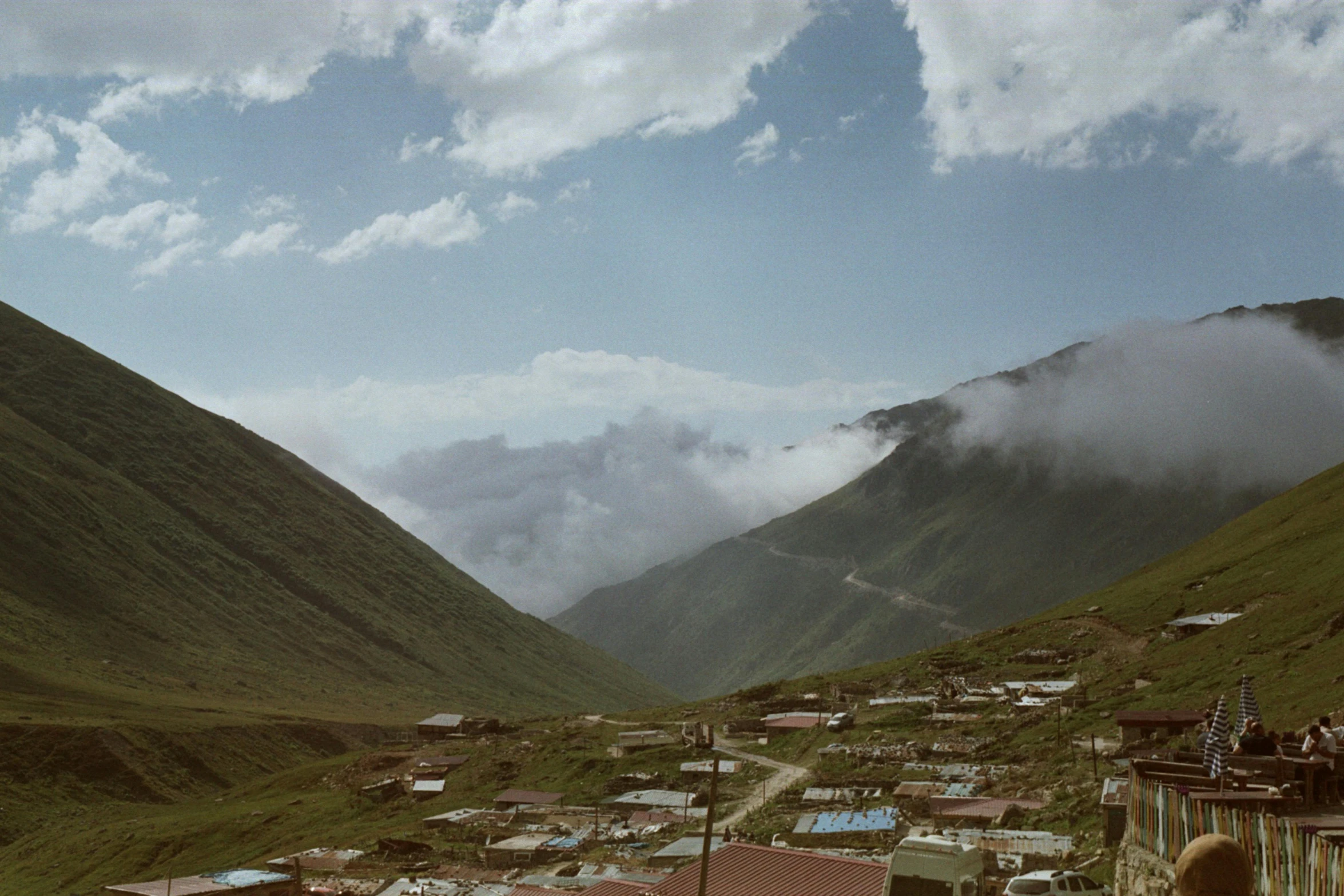 a village sits between hills as clouds loom in the background