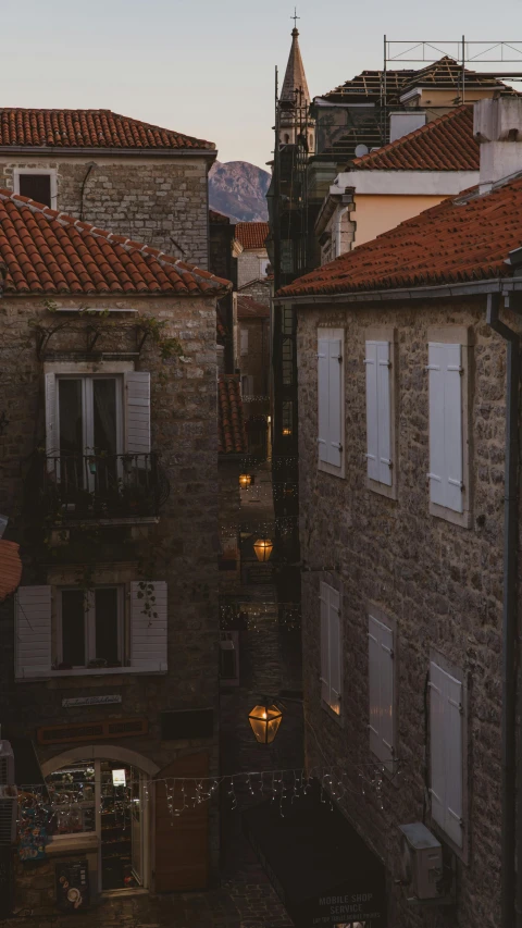 a brick city building has a small lamp in the alley