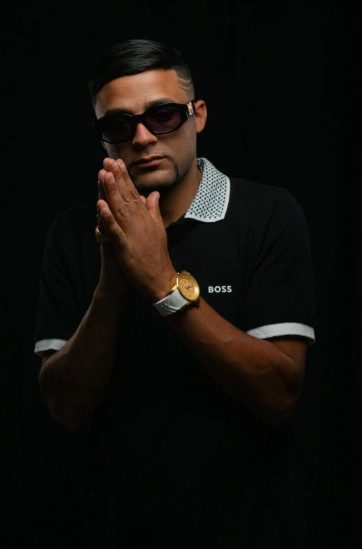 a man in sunglasses is standing and holding his hands together