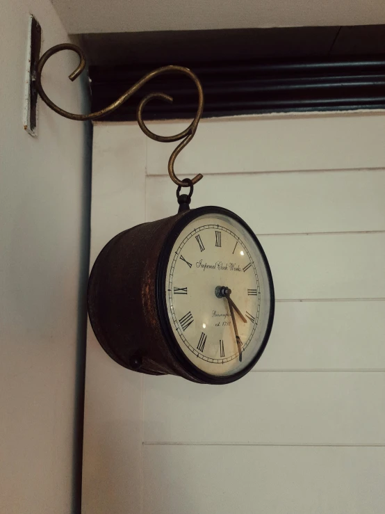 a black clock hanging from the side of a garage