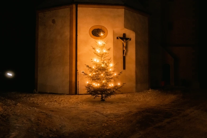 the cross is next to a small tree outside at night