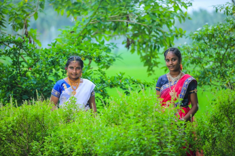 two women pose for the camera in a green area