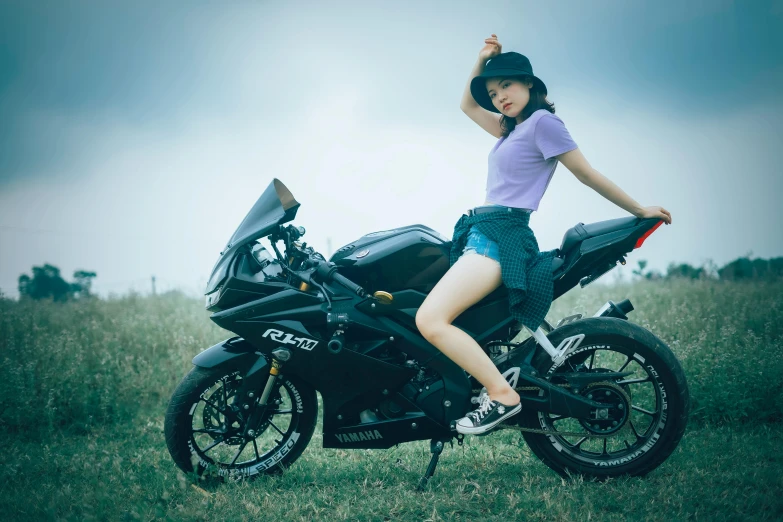 girl on motorbike leaning on her head with hat