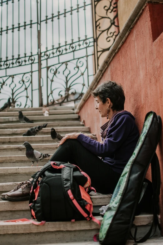 a woman is sitting on the steps next to luggage