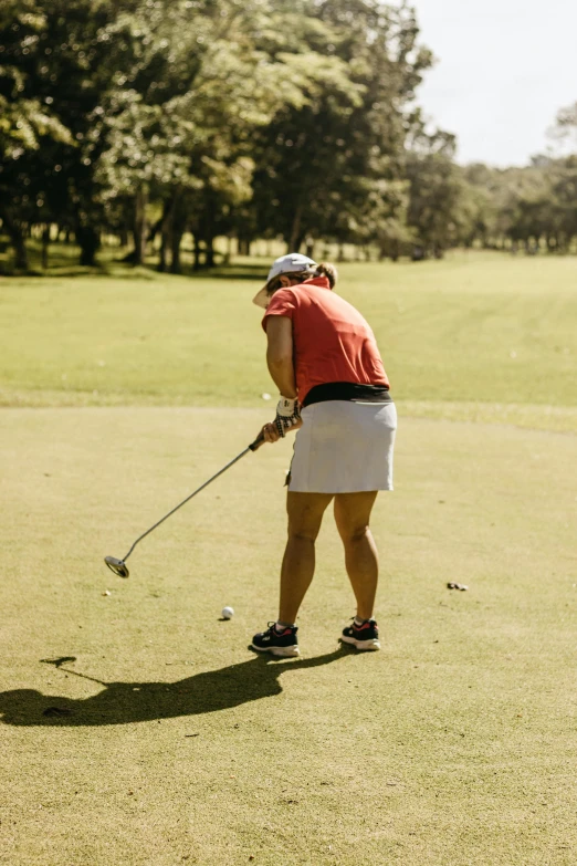 woman standing on golf green holding club about to tee - off